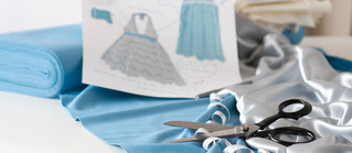 Ein Modeentwurf auf einem großen Tisch unter einer blaueb Stoffrolle.