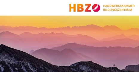 Das Bild zeigt eine malerische Berglandschaft bei Sonnenuntergang mit sanften Hügeln und farbenfrohem Himmel im Hintergrund.