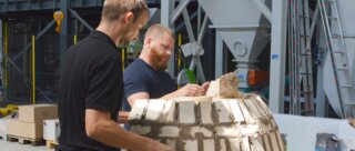 Zwei Männer arbeiten gemeinsam an einem Mauerwerk. Sie formen eine Kuppel aus Steinen und Mörtel in einer Werkstatt. Ambitionierte Bauarbeiten.
